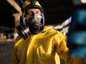 Operatore in tuta protettiva impegnato nella misurazione di inquinanti chimici e biologici in un luogo di lavoro